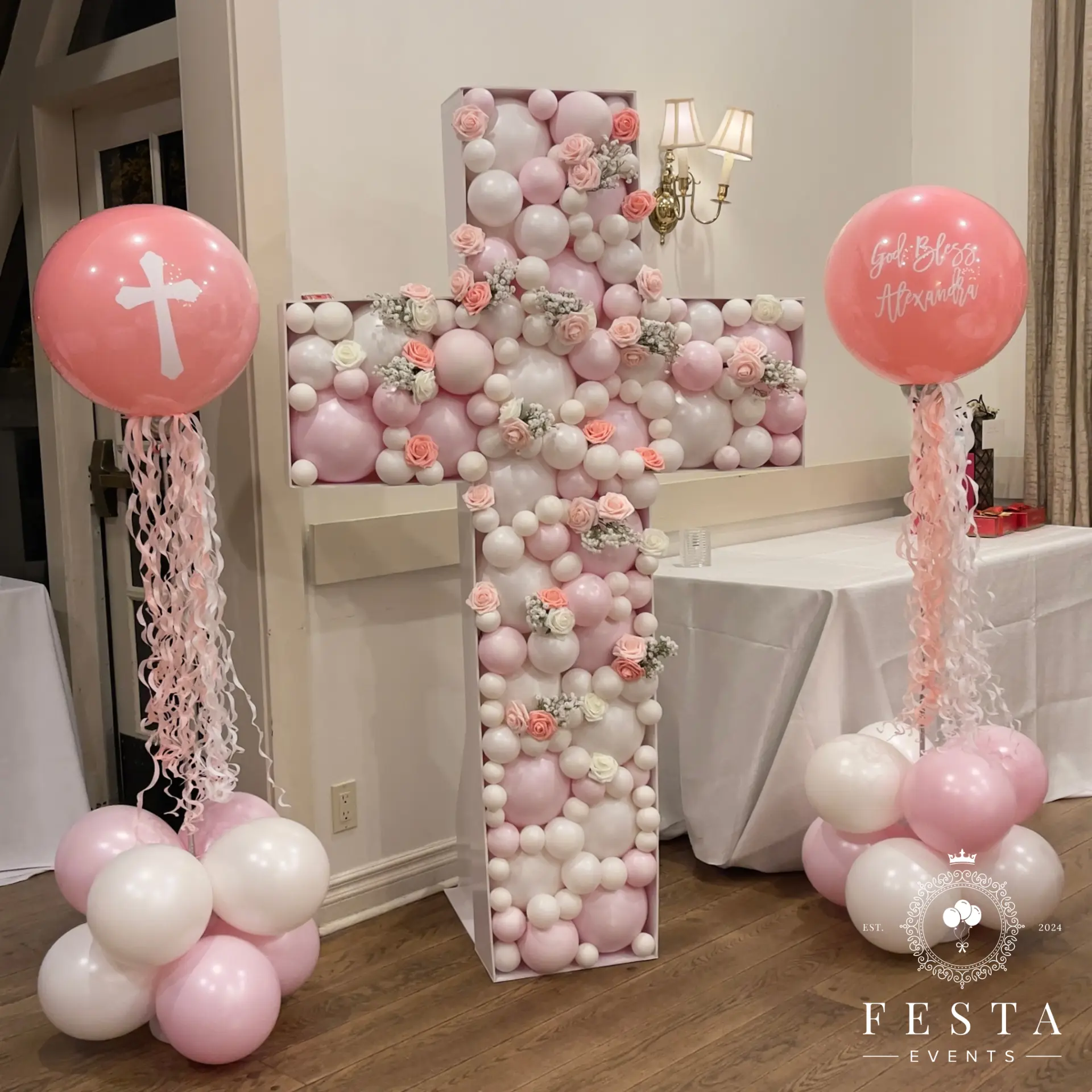 Pink and white balloon mosaic cross with floral accents and personalised balloons